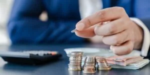 Main comptant des pièces de monnaie devant une calculatrice